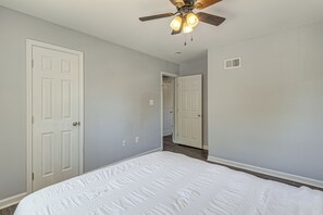 Ein Schlafzimmer mit einem Bett, einem Deckenventilator und zwei weißen Türen.