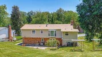A two-story house with a brick facade, a front porch, and a small garden area.