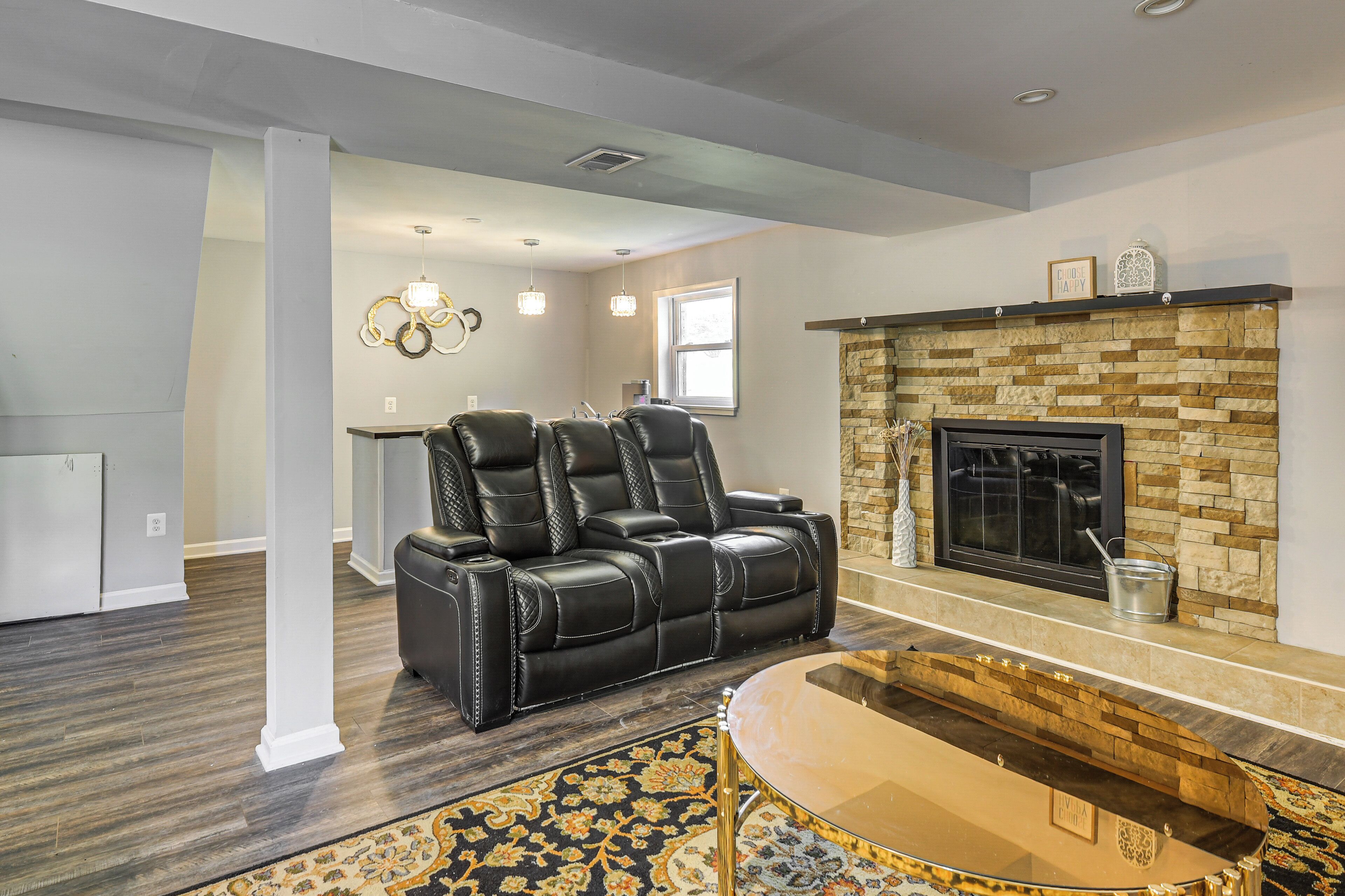 A living room with a fireplace, leather recliner, and a glass coffee table.