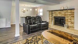 A living room with a fireplace, leather recliner, and a glass coffee table. - Easy Hwy Trip to DC! Group Retreat w/ Yard (Woodbridge)