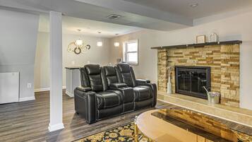 A living room with a fireplace, leather recliner, and a glass coffee table.