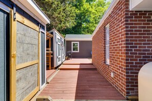 A narrow wooden deck leading to a brick building with a window and a door.