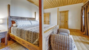 A wooden bed with a headboard, a ceiling fan, and a door in a room with wooden floors. - Franklin Cabin w/ Hot Tub, Theater & Fire Pit! (Franklin)