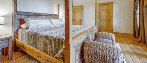 A wooden bed with a headboard, a ceiling fan, and a door in a room with wooden floors.