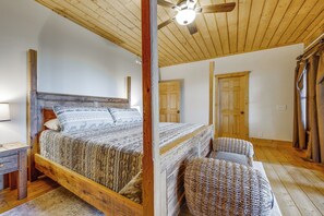 Ein Bett mit Holzkopfstütze, Deckenventilator und einer Tür in einem Zimmer mit Holzböden.