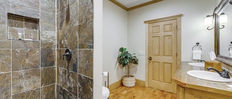 A bathroom with a shower, toilet, sink, and wooden cabinets.