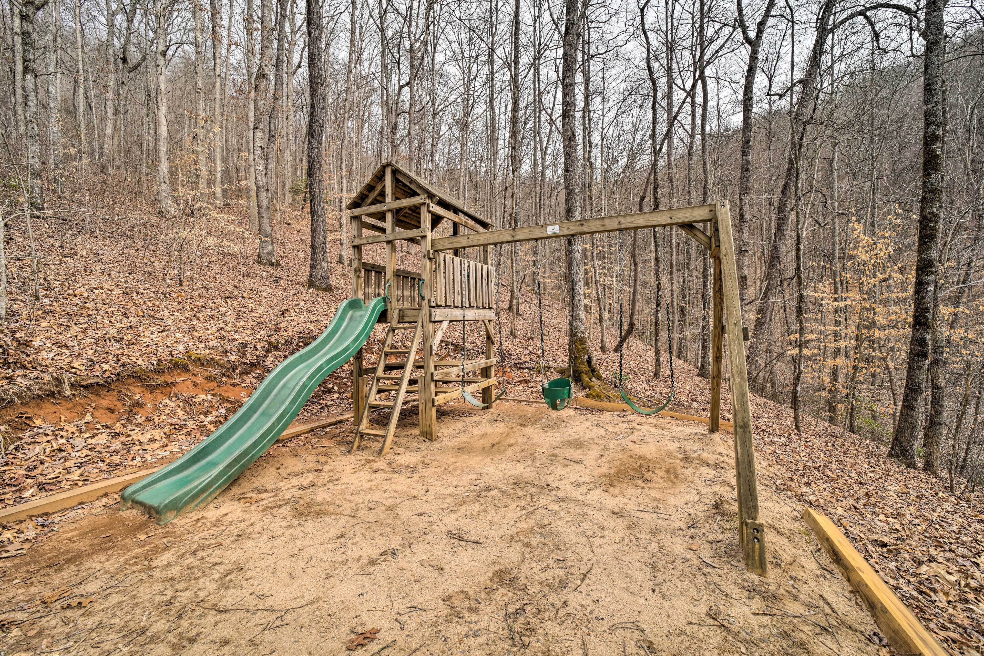A wooden play structure with a slide in a forested area.