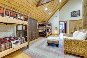 A loft-style bedroom with bunk beds, a sofa, and a large wardrobe. - Franklin Cabin w/ Hot Tub, Theater & Fire Pit! (Franklin)