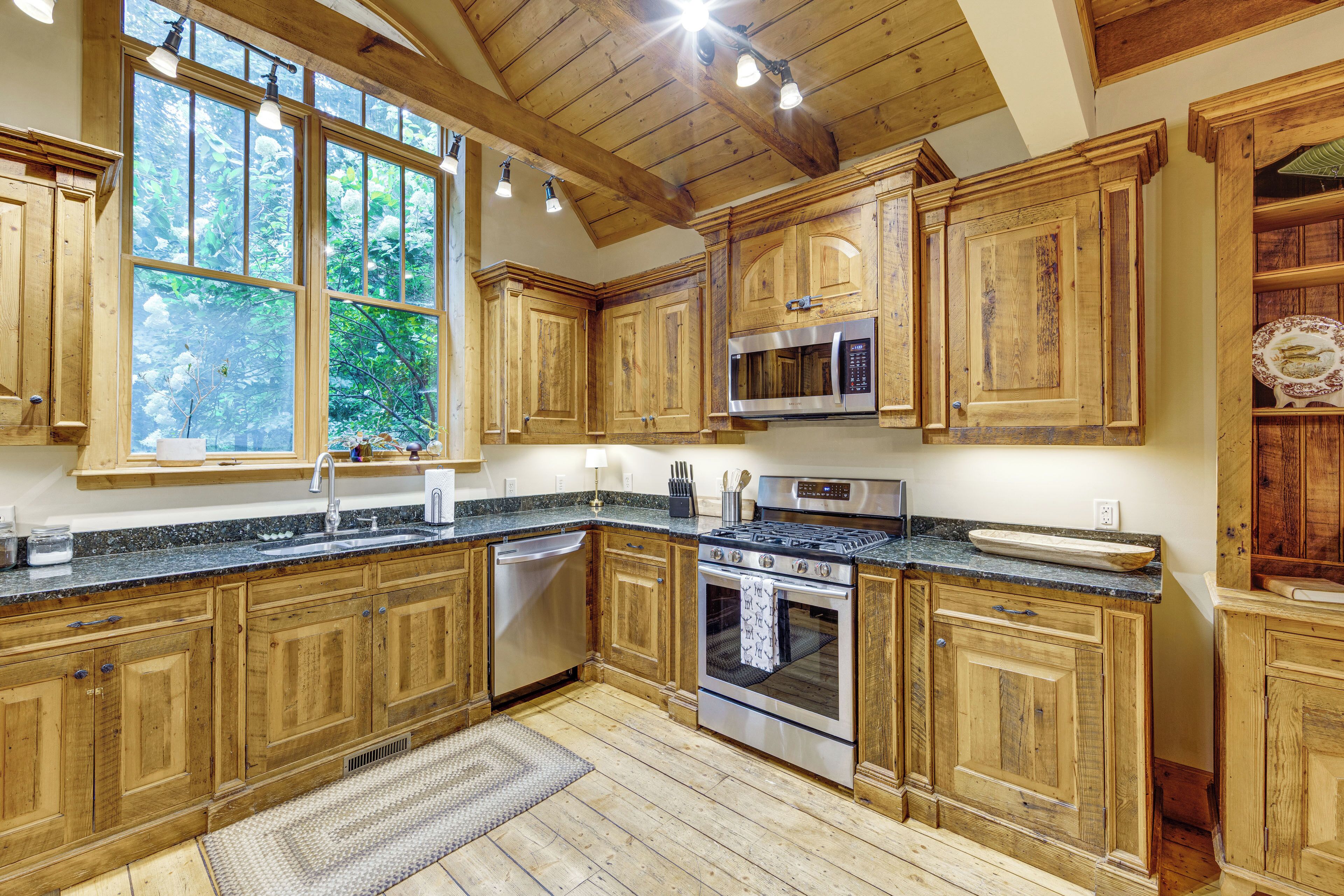 Una cocina con armarios de madera, un microondas de acero inoxidable y un horno empotrado.