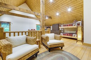 Ein Holzinnenraum mit Korbmöbeln, einem Etagenbett und einer Holzbalkendecke.