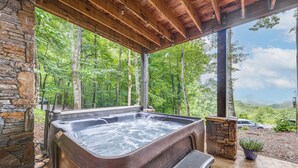 A hot tub under a wooden pergola with a stone wall, surrounded by a forest. - Franklin Cabin w/ Hot Tub, Theater & Fire Pit! (Franklin)