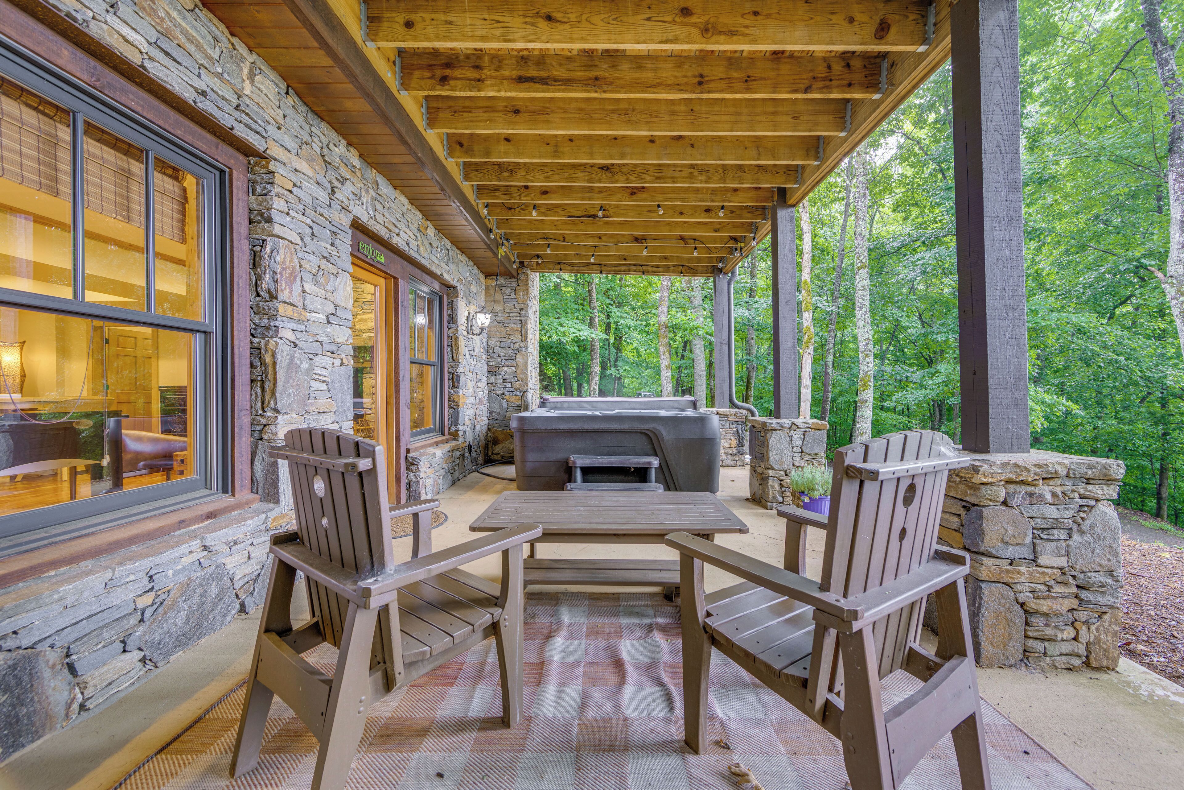 An outdoor patio with stone walls, wooden furniture, and a grill.