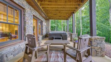 An outdoor patio with stone walls, wooden furniture, and a grill.