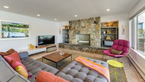 Una sala de estar moderna con chimenea de piedra, televisor de pantalla plana y asientos cómodos.