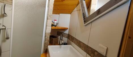 A bathroom with a white sink, wooden countertop, and a mirror.