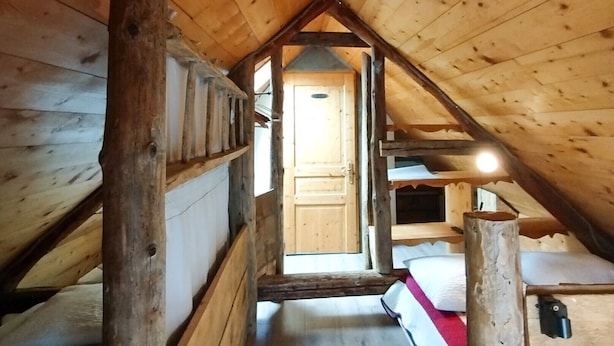 A wooden attic room with bunk beds, a wooden door, and a sloped ceiling. - Chalet Magui, Saint-sorlin-d\"arves (Saint-Sorlin-d'Arves)