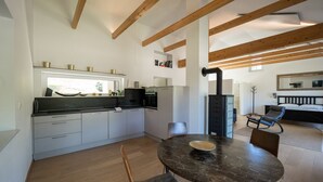A modern kitchen with white cabinets, a black countertop, and a wood beam ceiling. - WaldLoft - Southern Styria (Heimschuh)
