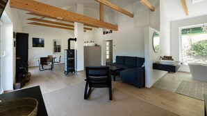 A spacious living area with a sofa, a dining table, and a kitchen area. - WaldLoft - Southern Styria (Heimschuh)