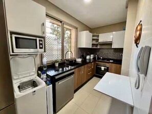 Eine Küche mit Mikrowelle, Kühlschrank, Spüle und Schränken.