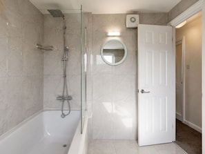 A bathroom with a glass-enclosed shower, a white bathtub, and a door leading to another room. - Cosy ,Comfortable house with a home-from-home feel. (Hayes)