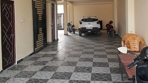 A corridor with a tiled floor, a parked car, and a motorcycle.