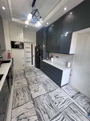 Une cuisine moderne avec des meubles de couleur sombre, un four encastré, un réfrigérateur et un sol à motifs.