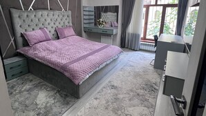Une chambre à coucher avec un grand lit, une coiffeuse, un miroir et une vue sur l’extérieur.