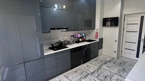 Une cuisine moderne avec des meubles de couleur sombre, un four encastré, un four à micro-ondes et un lave-vaisselle.