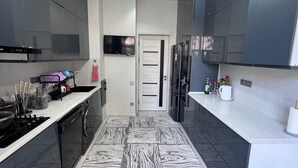 Une cuisine moderne dotée d’un îlot central, d’appareils électroménagers intégrés et d’un sol à motifs.