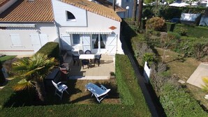 Ein Haus mit Terrasse, Tisch, Stühlen und einer Liege.