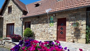 Edifici de pedra amb teulada vermella, una porta de fusta i un rètol que indica un allotjament rural.