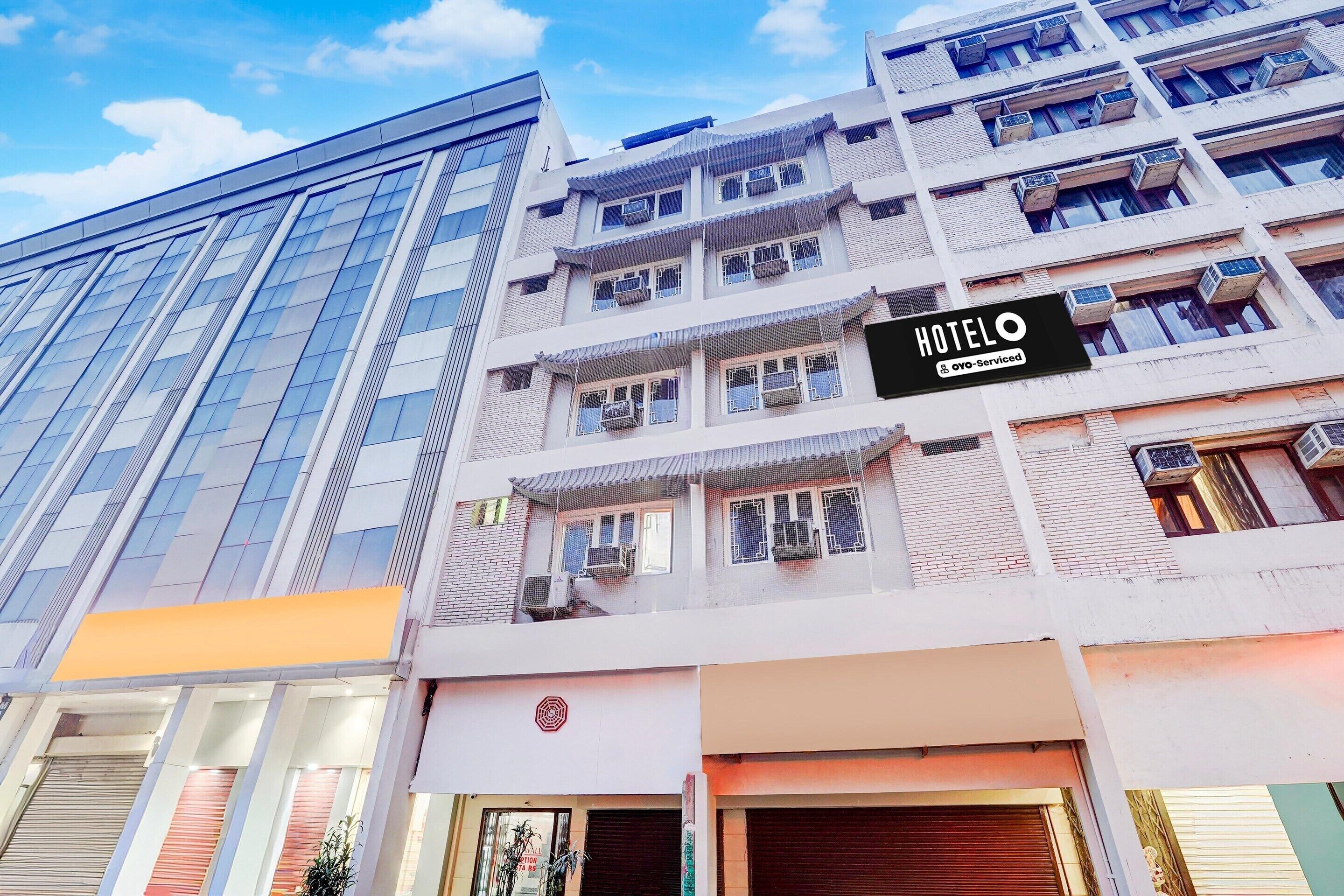 Um hotel com fachada moderna, várias varandas e uma placa bem visível.