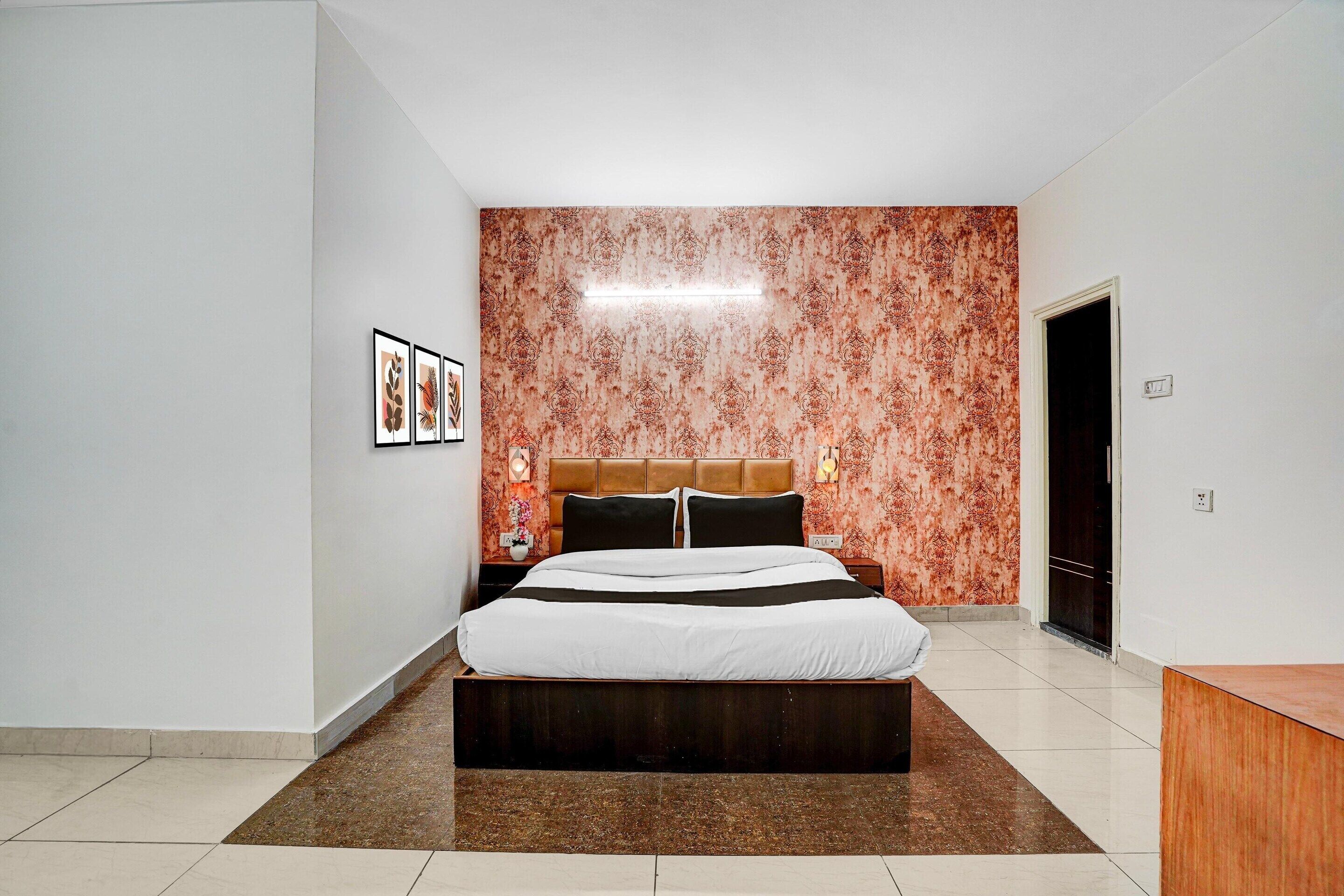 A modern bedroom with a large bed, a headboard, a nightstand, and a wall with a patterned wallpaper.