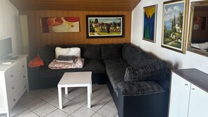 Ein Wohnzimmer mit einer Couch, einem kleinen Tisch und einem Schrank. An den Wänden befinden sich Gemälde.