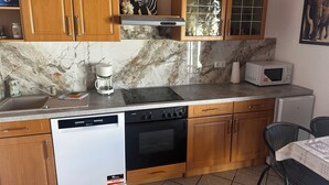Eine Küche mit Holzausstattung, Backofen, Geschirrspüler, Kaffeemaschine und Mikrowelle.