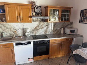 A kitchen with wooden cabinets, a built-in oven, a dishwasher, a coffee maker, and a microwave.