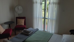 A room with a bed, a red chair, a small table, and a fan. - Two bedroom apartment with private parking, close to the beach and a sea (Selce)