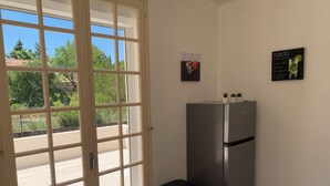 A kitchen with a stainless steel refrigerator, a trash bin, a door with a window, and a wall with a coffee cup and a mojito glass.