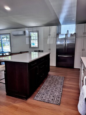 A modern kitchen with a central island, stainless steel appliances, and a view to the outdoors.