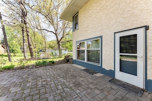 Een huis met een betegeld terras, een voordeur en een raam.