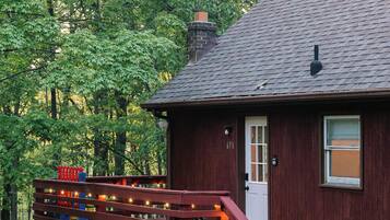 A wooden cabin with a porch, a chimney, and a number '671' on the door.