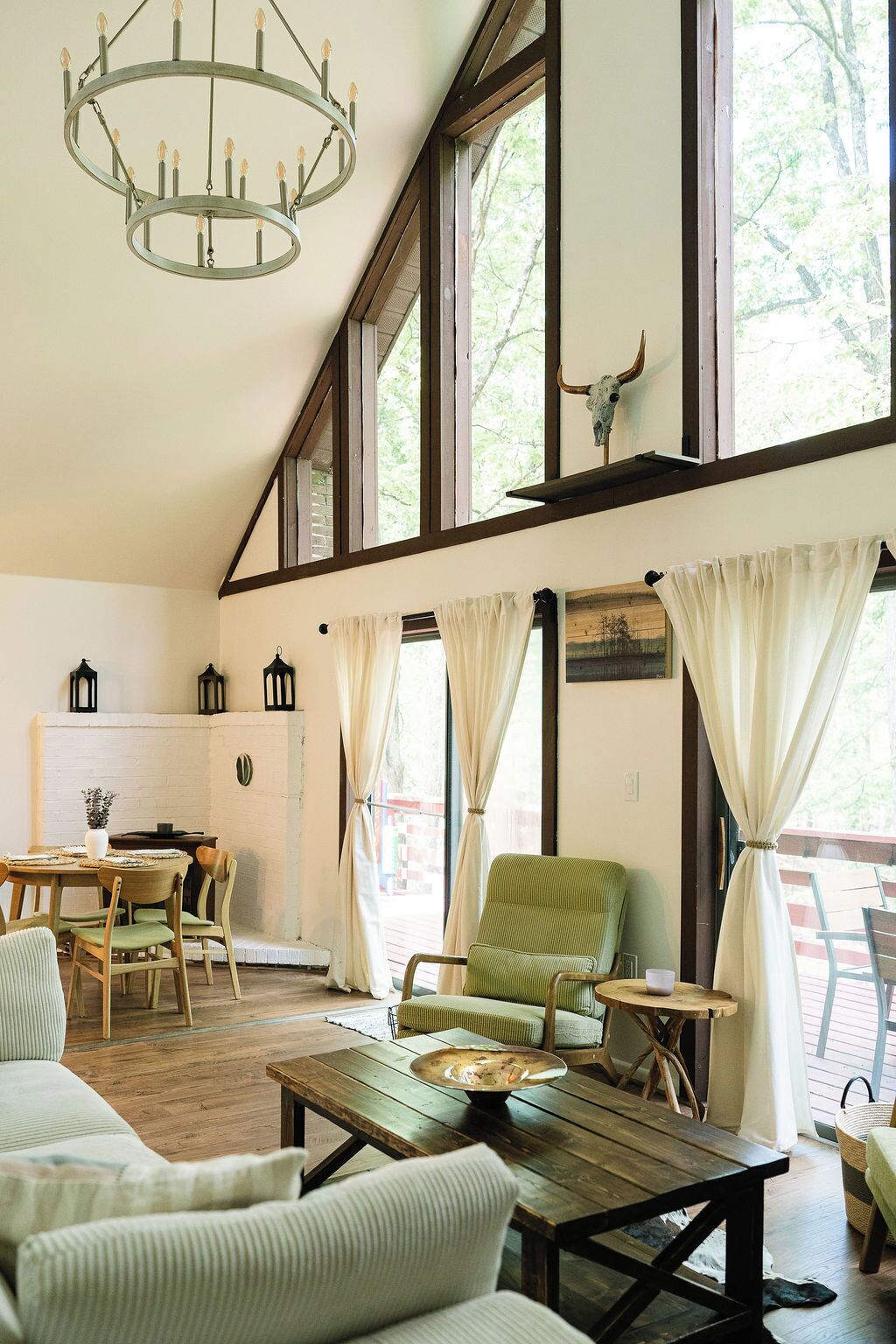 A spacious room with a high ceiling, large windows, a chandelier, and a rustic decor including a cow skull.