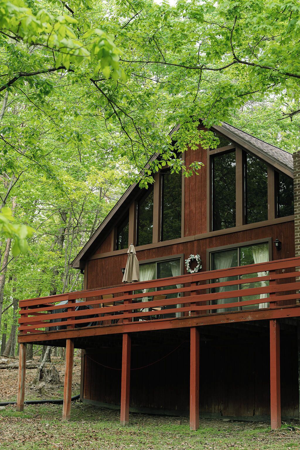 A wooden cabin with a balcony, surrounded by trees.