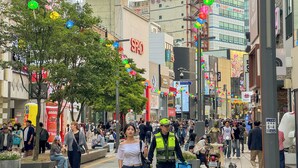 A busy urban street with pedestrians, shops, and a variety of signage. - Amoon stay (Busan)