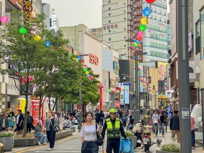 A busy urban street with pedestrians, shops, and a variety of signage. - Amoon stay (Busan)