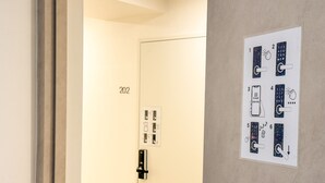 Porta de quarto de hotel com fechadura eletrônica, painel de controle fixado na parede e o número '202'.