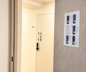 A hotel room door with a keypad lock, a wall-mounted control panel, and a door number '202'. - Amoon stay (Busan)