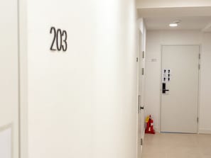 A hallway with a door labeled '203' and another door labeled '201' with a fire extinguisher and a sign on the wall.