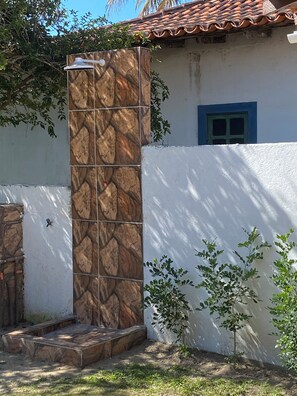 Ein Haus mit einer Kachelsaüle, einem blauen Fenster und einem kleinen Baum im Garten.