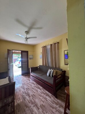 Ein Zimmer mit einer Couch, einem Deckenventilator, einem Tisch und einem Stuhl.